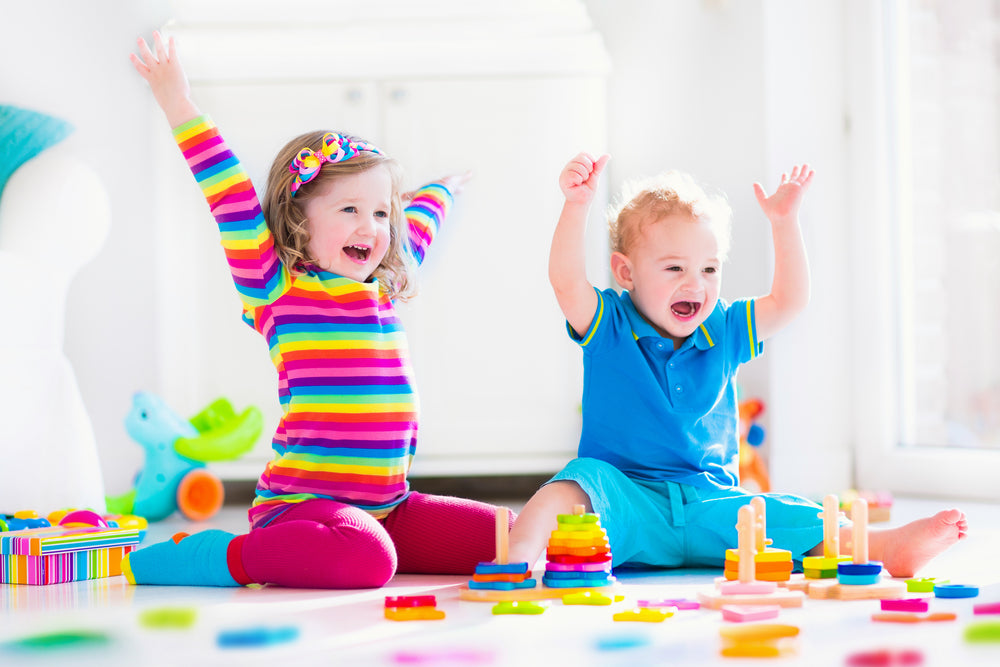 Two kids happily build towers with wooden toy blocks
