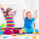 Two kids happily build towers with wooden toy blocks